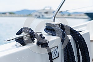 Detail of an anchor rope on a yacht, Stainless steel boat mooring cleat with knotted rope mounted on white yacht deck