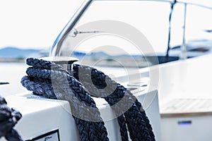 Detail of an anchor rope on a yacht, Stainless steel boat mooring cleat with knotted rope mounted on white yacht deck