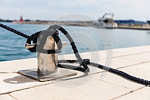 Detail of an anchor rope on a yacht, Stainless steel boat mooring cleat with knotted rope mounted on white yacht deck