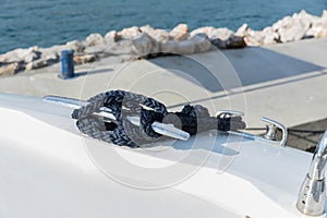 Detail of an anchor rope on a yacht, Stainless steel boat mooring cleat with knotted rope mounted on white yacht deck