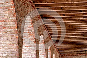 Detail of an arched brick structure with exposed wooden beam rafters