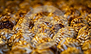 Detail of an assortment of sweet golden pine nut panellet cupcakes with a very toasted focused row on a tray fresh from the photo