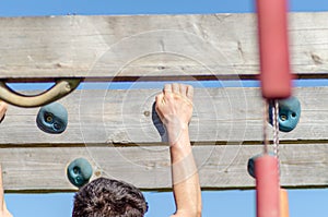 Detail of an athlete hanging from an obstacle at an obstacle course race, OCR