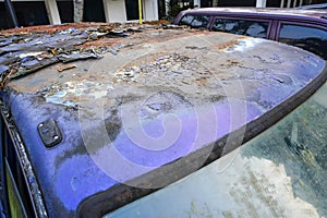 Detail of badly rusted and peeling automobile paint on the car's roof. automobile that is broken and rusted