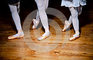 Detail of ballet dancers& x27; feet of three girls standing in special position on wooden floor