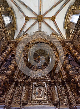 Detail of a baroque chapel meticulously carved in wood with golden colors full of religious figures with Jesus Christ crucified in