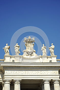 Detail from baroque Saint Peter`s colonnade with beautiful statues of saints and Pope Alexander VII coat of arms. Vatican City