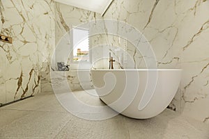 Detail of a bathroom with marble walls, continuous worktop in the