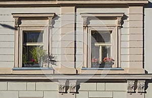 Detail of beige facade of old prague tenement house Windows with flower boxes