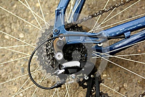 Detail of a bicycle wheel with spokes, chain and gearshift hub.