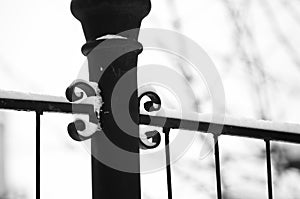 Detail of a black metal fence on a white snow background during winter