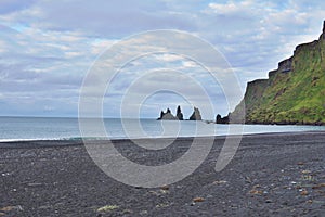 Detail of a black sand on the famous dark beach in the Icelandic town Vik with the rock cliffs in the ocean