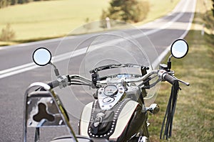 Detail of black shiny high-speed motorcycle parked on roadside on blurred sunny outdoors background.