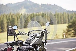 Detail of black shiny high-speed motorcycle parked on roadside on blurred sunny outdoors background.