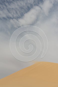 Detail of blowing sand in the wind of the top of a sanddune, rescaping the landscape and forming new sanddunes