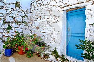 Detail of blue door, white stone wall and colorful flowers