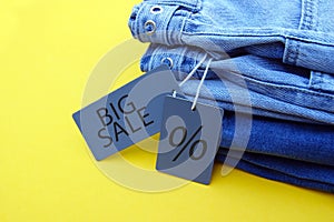 Detail of blue jeans, grey labels and inscription Big Sale on yellow background.