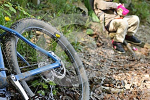 Detail of blue mountain bike in forest with resting kid