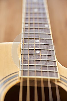 Detail of the body of a light wood guitar, soundhole, fretboards and strings