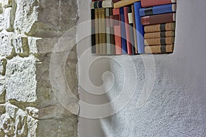 Detail of book shelf inside white wall in white open plan room bright interior wide angle stone wall, modern stylish loft