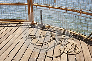 Detail of the bow of a tourist boat sailing, mooring rope on deck timbers