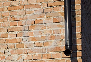 Detail of brick wall,, exterior corner of building with new drainpipe. Construction and rain sewage installation concept