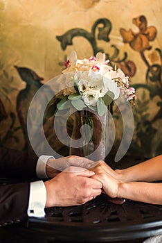 Detail of bride`s roses bouquet and hands holding