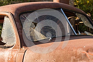 Detail of the broken front glass of an old rusty and abandoned pickup in Maryhill