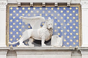 Detail of a building in Venice where a winged lion appears holding a book