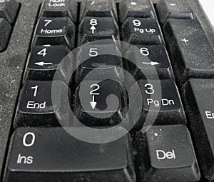 Detail of the buttons of a dusty black plastic european computer keyboard. Black old dusty computer keyboard