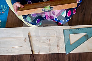 Detail of child helping with measuring wooden plank to make shelves.