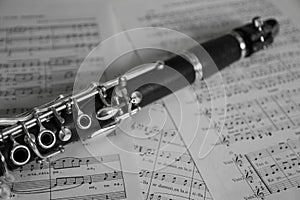 Detail of a clarinet on some music sheets. Black and white image