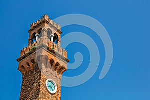 Detail of clock tower made of bricks with sunny blue sky in Murano