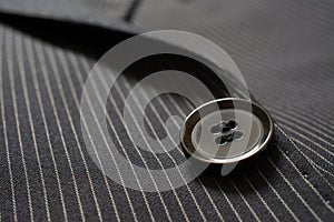 Detail of closeup of suit button on pin stripped cloth. Tailoring background