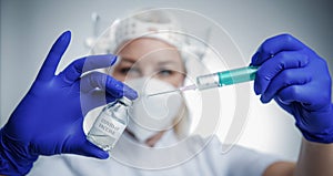 Detail closeup of syringe needle and ampoule , nurse taking injection shot,hands in blue protective gloves holding