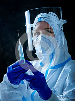 Detail closeup of syringe needle and ampoule , nurse taking injection shot,hands in blue protective gloves holding