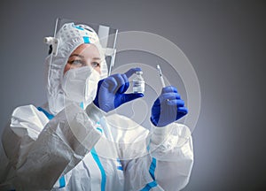 Detail closeup of syringe needle and ampoule , nurse taking injection shot,hands in blue protective gloves holding