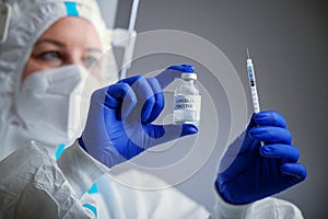 Detail closeup of syringe needle and ampoule , nurse taking injection shot,hands in blue protective gloves holding