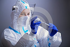 Detail closeup of syringe needle and ampoule , nurse taking injection shot,hands in blue protective gloves holding