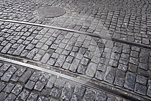 detail of a cobblestone street, with a tramway and a sewer manhole, floor of a street in Lisbon, Portugal