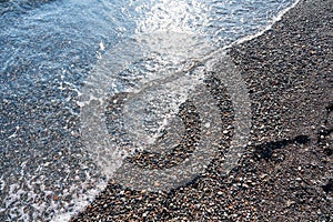 Detail of cobblestones in the transparent water of the famous Vlychada Beach, Santorini