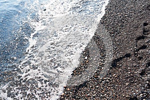 Detail of cobblestones in the transparent water of the famous Vlychada Beach, Santorini