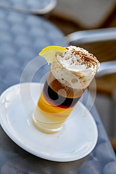 Detail of a coffee combined with whiskey condensed milk cinnamon cream and lemon in a glass cup