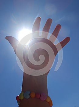 Detail color photography of womans hand catching sun rays and blue sky