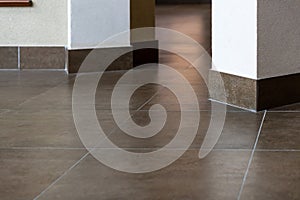 The detail of the corner baseboard on the wall and granite tiles on the floor. A white wall with a copy space, decorated with