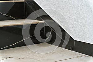 The detail of the corner baseboard on the wall and granite tiles on the floor. A white wall with a copy space, decorated with