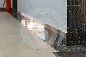 The detail of the corner baseboard on the wall and granite tiles on the floor. A white wall with a copy space, decorated with