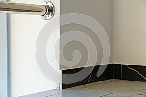 The detail of the corner baseboard on the wall and granite tiles on the floor. A white wall with a copy space, decorated with