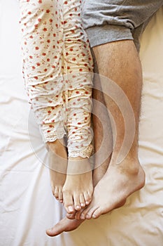 Detail Of Couple's Legs Relaxing In Bed