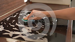 Detail cropped shot of unrecognizable man cleaning induction stove in kitchen. Closeup hands of housewife wiping cooking